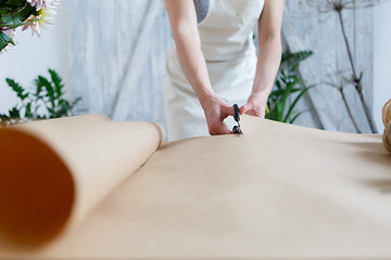 Image showing Woman florist cuts wrapping paper