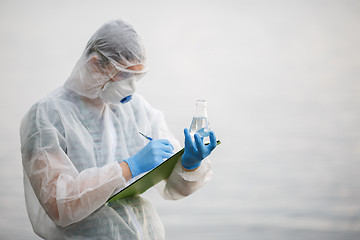 Image showing Ecologist writes in folder ,river