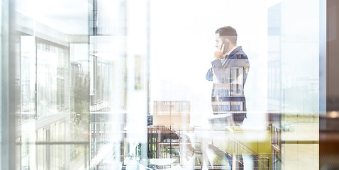 Image showing Businessman talking on a mobile phone while looking through window.