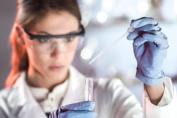 Image showing Young scientist pipetting in life science laboratory.