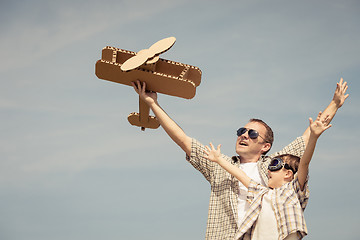 Image showing Father and son playing with cardboard toy airplane in the park a