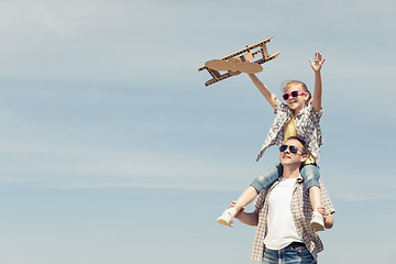 Image showing Father and daughter playing with cardboard toy airplane in the p