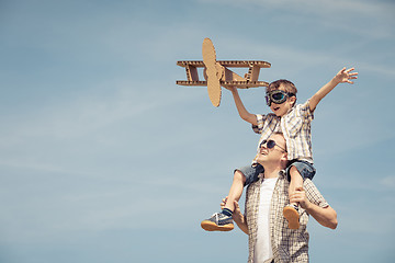 Image showing Father and son playing with cardboard toy airplane in the park a