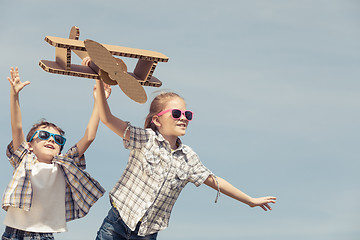 Image showing Little kids playing with cardboard toy airplane in the park at t