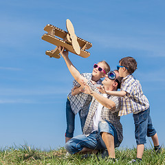 Image showing Father and children playing with cardboard toy airplane in the p