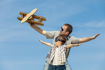 Image showing Father and son playing with cardboard toy airplane in the park a