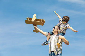 Image showing Father and son playing with cardboard toy airplane in the park a