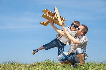 Image showing Father and son playing with cardboard toy airplane in the park a