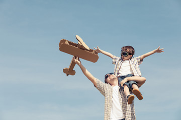 Image showing Father and son playing with cardboard toy airplane in the park a