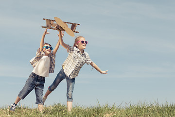 Image showing Little kids playing with cardboard toy airplane in the park at t