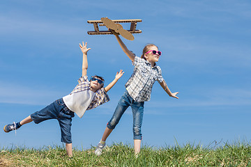 Image showing Little kids playing with cardboard toy airplane in the park at t