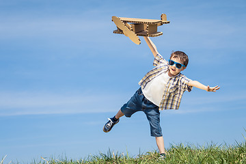 Image showing Little boy playing with cardboard toy airplane in the park at th