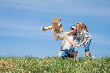 Image showing Father and daughter playing with cardboard toy airplane in the p