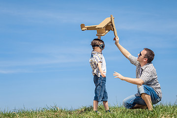 Image showing Father and son playing with cardboard toy airplane in the park a