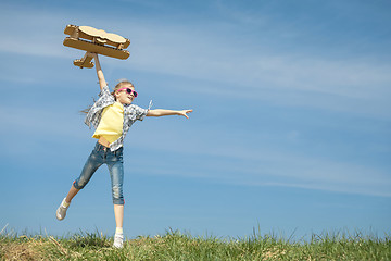 Image showing Little girl playing with cardboard toy airplane in the park at t