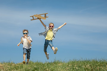 Image showing Little kids playing with cardboard toy airplane in the park at t