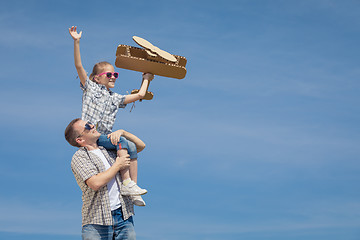 Image showing Father and daughter playing with cardboard toy airplane in the p