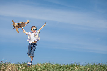 Image showing Little boy playing with cardboard toy airplane in the park at th