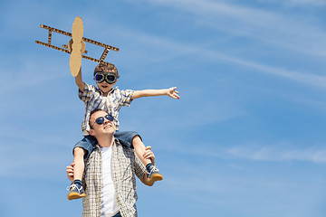 Image showing Father and son playing with cardboard toy airplane in the park a