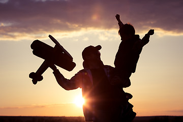 Image showing Father and son playing with cardboard toy airplane in the park a