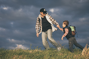 Image showing Father and son walking on the road at the day time.