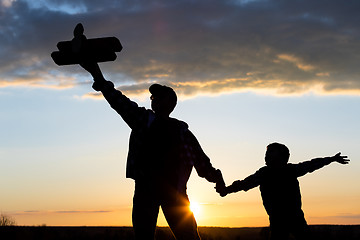 Image showing Father and son playing with cardboard toy airplane in the park a