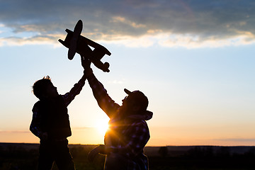 Image showing Father and son playing with cardboard toy airplane in the park a