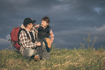 Image showing Father and son walking on the road at the day time.