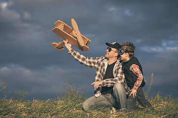 Image showing Father and son playing with cardboard toy airplane in the park a