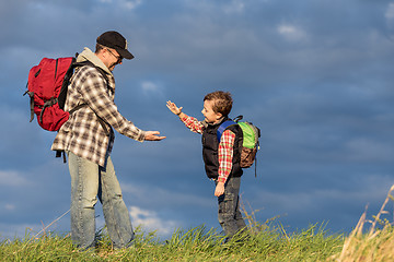 Image showing Father and son walking on the road at the day time.