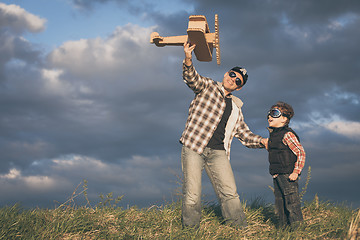 Image showing Father and son playing with cardboard toy airplane in the park a