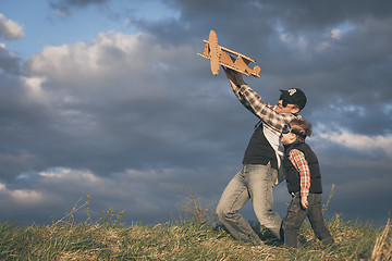 Image showing Father and son playing with cardboard toy airplane in the park a