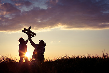 Image showing Father and son playing with cardboard toy airplane in the park a