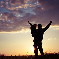 Image showing Father and son walking on the field at the sunset time.