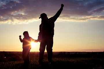 Image showing Father and son walking on the field at the sunset time.