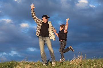 Image showing Father and son walking on the road at the day time.