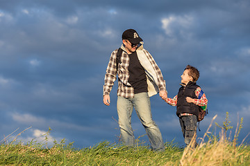 Image showing Father and son walking on the road at the day time.