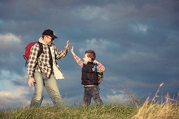 Image showing Father and son walking on the road at the day time.