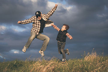 Image showing Father and son walking on the road at the day time.