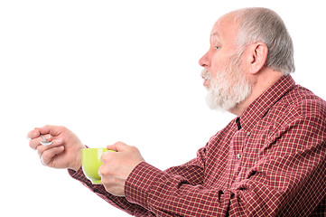 Image showing Cheerfull senior man with green cup and teaspoon, isolated on white