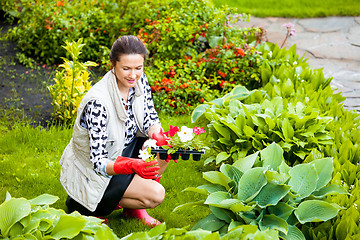 Image showing smiling middle-aged woman in red rubber gloves planting flowers