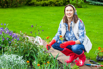 Image showing smiling woman in kerchief and red boots planting flowers