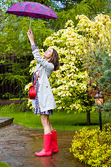 Image showing Beautiful smiling woman in red rubber boots and with an umbrella