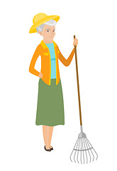 Image showing Senior caucasian farmer holding gardening rake.