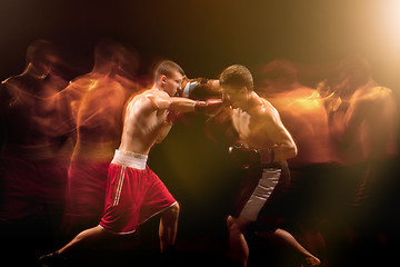 Image showing The two male boxers boxing in a dark studio