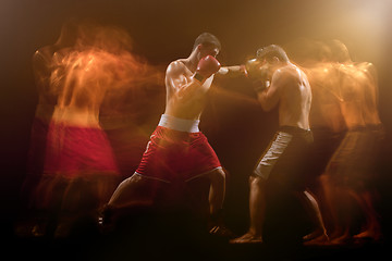 Image showing The two male boxers boxing in a dark studio