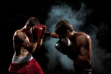 Image showing Two professional boxer boxing on black smoky background,