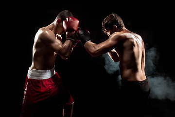 Image showing Two professional boxer boxing on black smoky background,