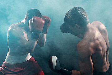 Image showing Two professional boxer boxing on black smoky background,