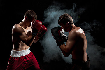 Image showing Two professional boxer boxing on black smoky background,